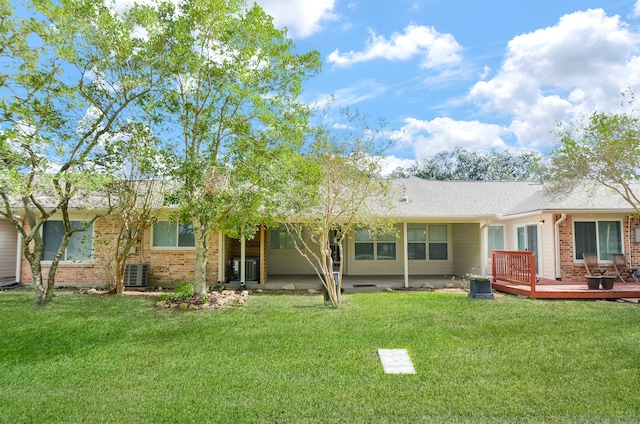 back of property featuring a wooden deck, cooling unit, and a lawn