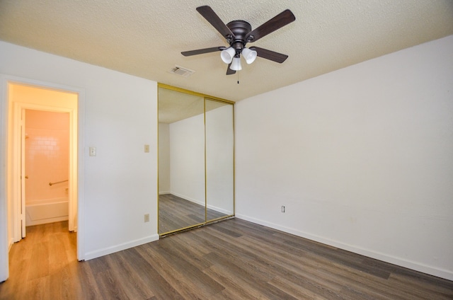 unfurnished bedroom with a closet, a textured ceiling, ceiling fan, and dark hardwood / wood-style flooring