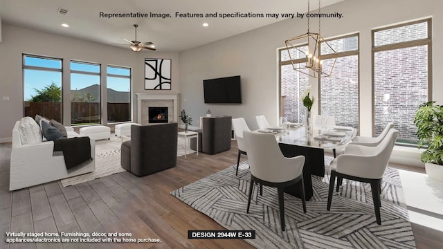 dining area with recessed lighting, visible vents, a glass covered fireplace, wood finished floors, and ceiling fan with notable chandelier