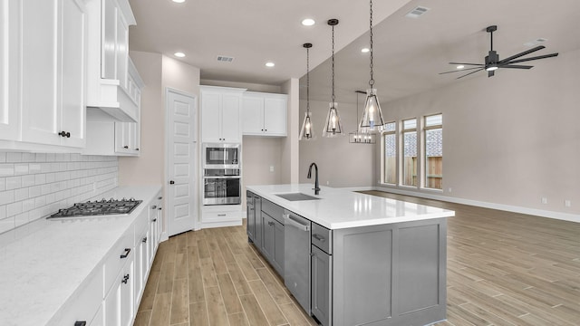 kitchen with stainless steel appliances, gray cabinets, white cabinetry, and a sink