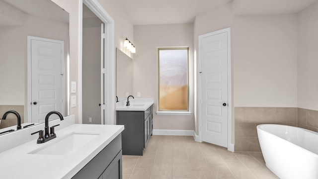 full bathroom featuring two vanities, a sink, and a freestanding bath