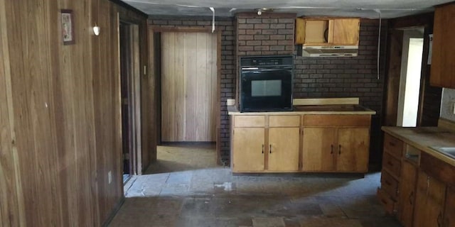 kitchen featuring oven and wood walls