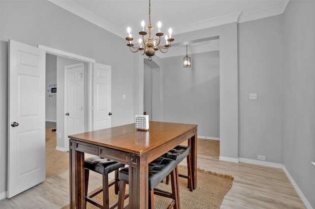 dining area with light hardwood / wood-style floors, crown molding, and a chandelier