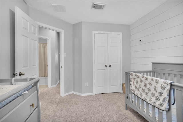 carpeted bedroom featuring a nursery area and a closet