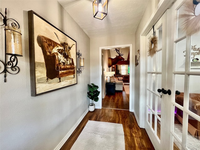 hall featuring dark wood-type flooring, french doors, and a textured ceiling