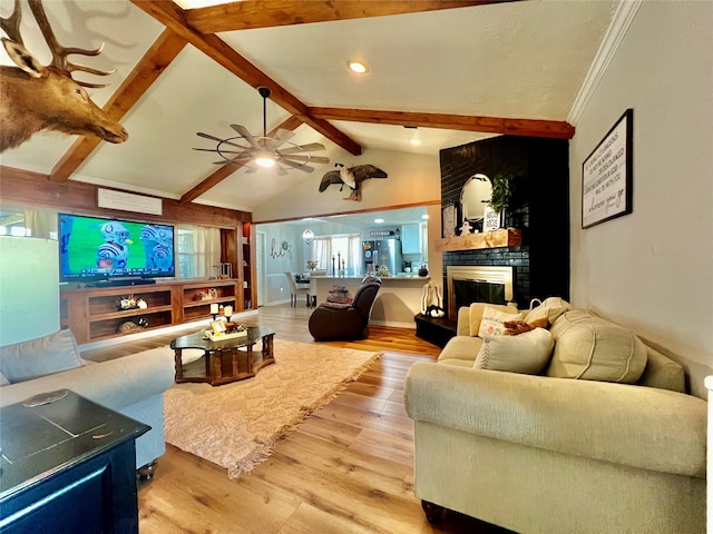 living room featuring lofted ceiling with beams, ceiling fan, a fireplace, and light hardwood / wood-style floors