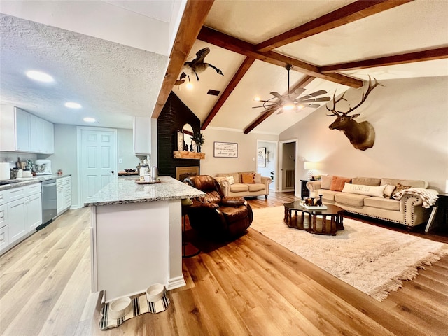 living room with ceiling fan, light hardwood / wood-style flooring, lofted ceiling with beams, and a textured ceiling