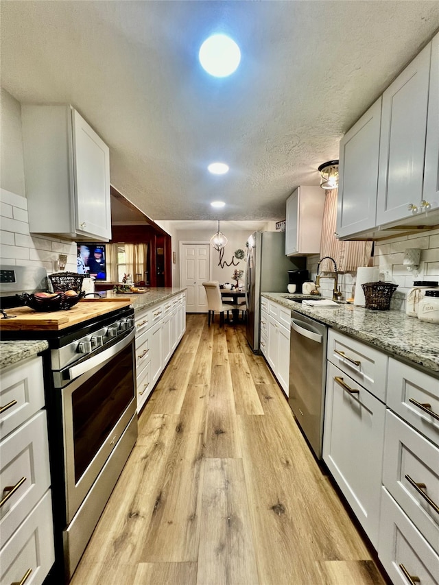 kitchen featuring white cabinetry, appliances with stainless steel finishes, sink, and light hardwood / wood-style flooring