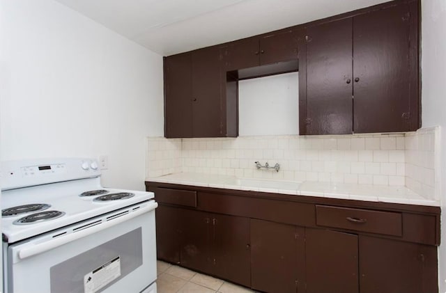 kitchen featuring light tile patterned floors, dark brown cabinetry, sink, and white range with electric cooktop