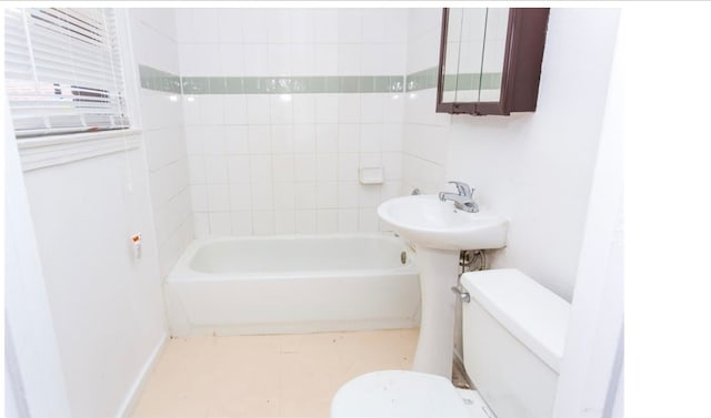 bathroom featuring toilet, a tub, and tile patterned floors