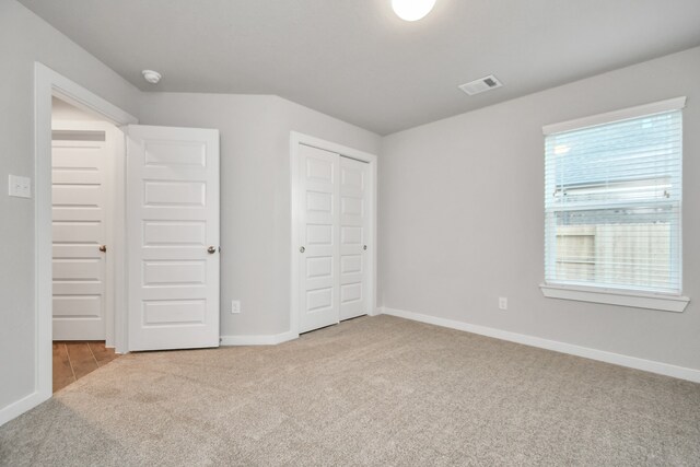 unfurnished bedroom featuring light carpet and a closet