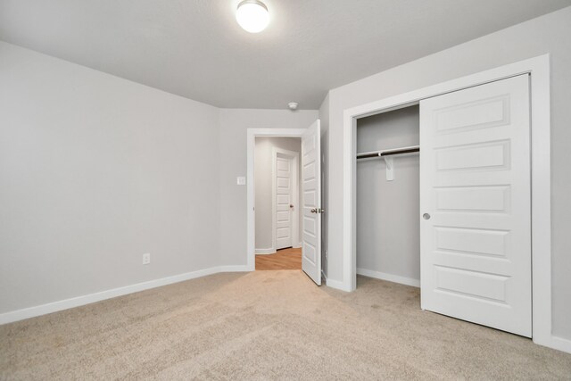 unfurnished bedroom with light carpet and a closet