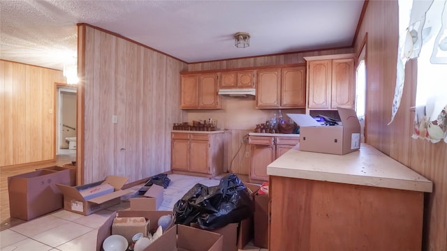 kitchen with light tile patterned flooring, a textured ceiling, and wood walls