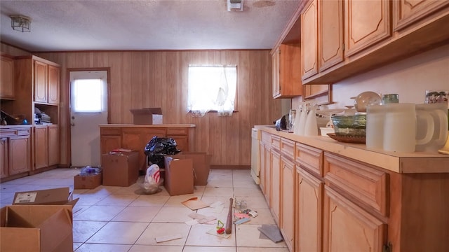 kitchen with wooden walls, light tile patterned flooring, and a textured ceiling