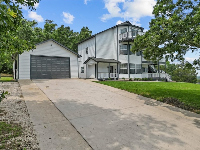 view of front of home with covered porch, a garage, a front lawn, and an outbuilding