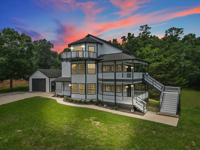 back house at dusk with a yard, an outdoor structure, a balcony, and a garage