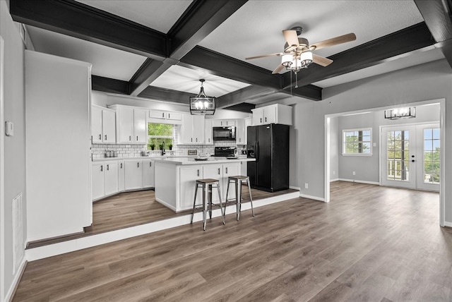 kitchen with black appliances, a center island, a kitchen breakfast bar, white cabinetry, and decorative light fixtures