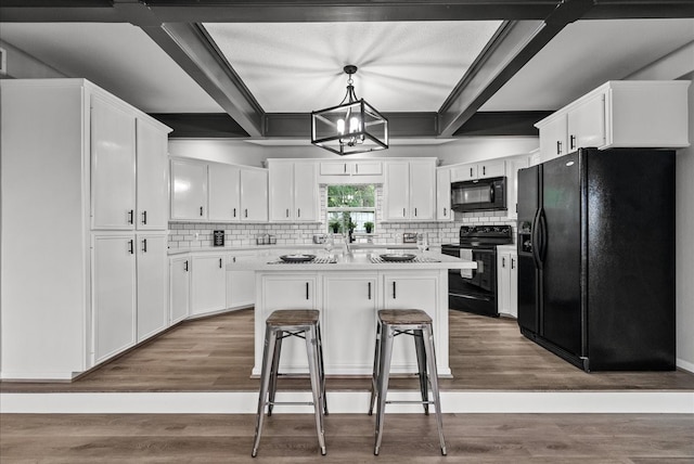 kitchen with black appliances, a center island, a kitchen bar, decorative light fixtures, and white cabinets