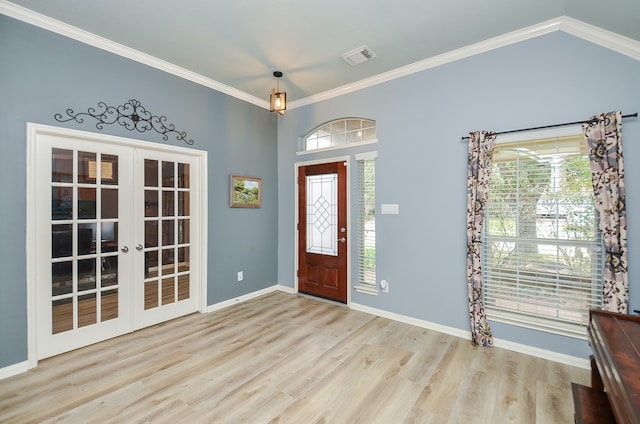 entrance foyer with light hardwood / wood-style floors, french doors, ornamental molding, and a healthy amount of sunlight