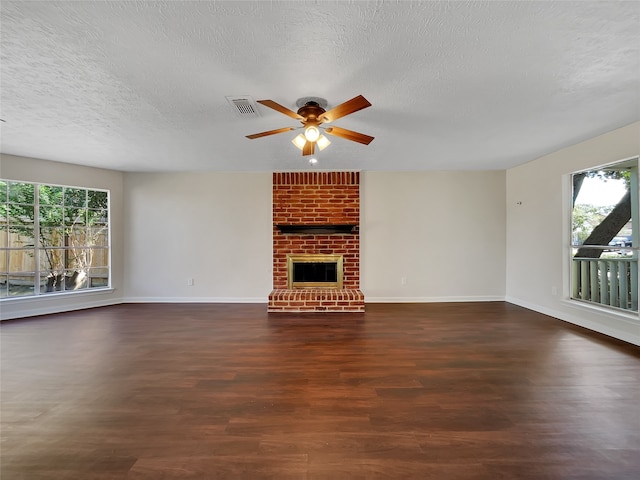 unfurnished living room featuring a wealth of natural light, a textured ceiling, and dark hardwood / wood-style floors