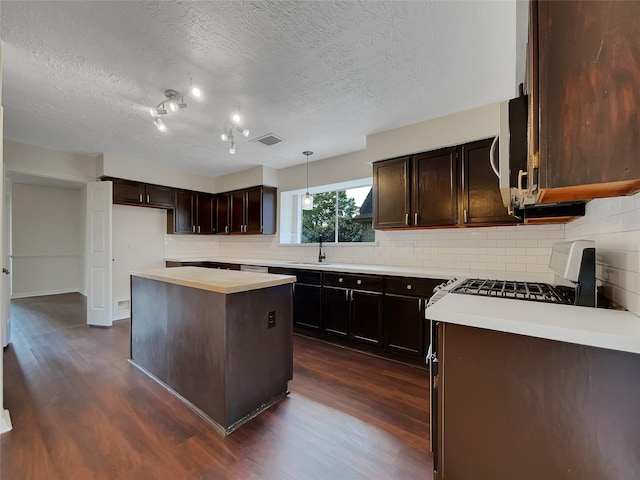14718 W Bend Dr, Houston, TX 77082 - kitchen featuring dark wood finished floors, gas range, tasteful backsplash, a kitchen island, and a textured ceiling