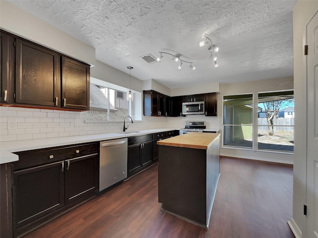 14718 W Bend Dr, Houston, TX 77082 - kitchen with appliances with stainless steel finishes, wooden counters, dark wood-style flooring, a sink, and decorative backsplash