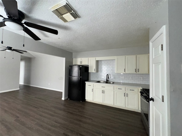 kitchen with dark hardwood / wood-style floors, black fridge, white cabinetry, and stainless steel range oven