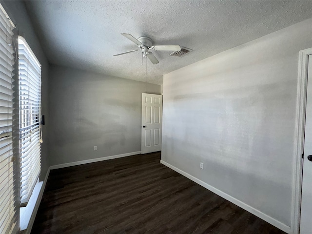 empty room featuring a textured ceiling, ceiling fan, and dark wood-type flooring