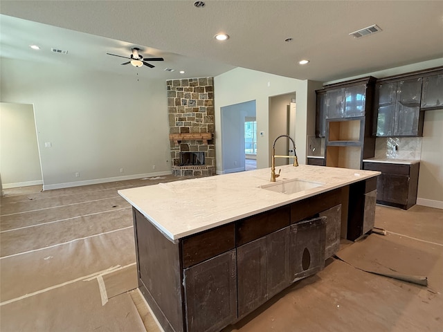 kitchen featuring dark brown cabinetry, a kitchen island with sink, ceiling fan, and sink