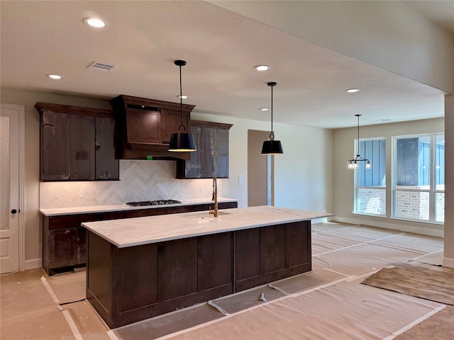 kitchen featuring dark brown cabinetry, sink, an island with sink, and stainless steel gas cooktop