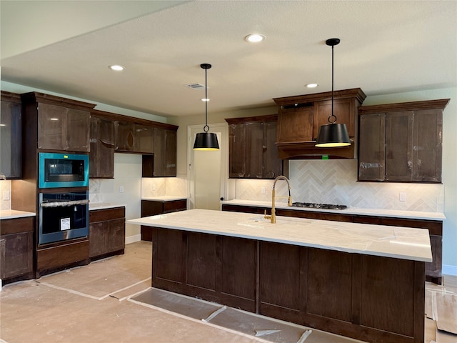 kitchen featuring backsplash, a kitchen island with sink, hanging light fixtures, and appliances with stainless steel finishes