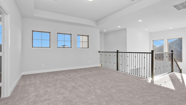 carpeted empty room with a raised ceiling