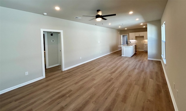 unfurnished living room featuring ceiling fan, sink, and light hardwood / wood-style flooring