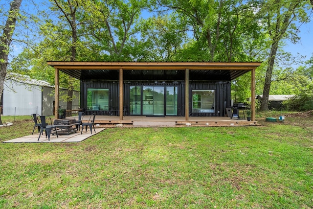 back of property with a yard, a wooden deck, and a fire pit