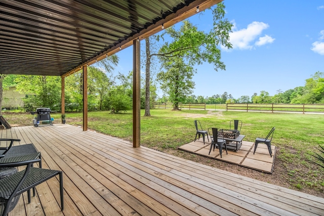 wooden terrace featuring a patio area, a grill, a lawn, and a rural view