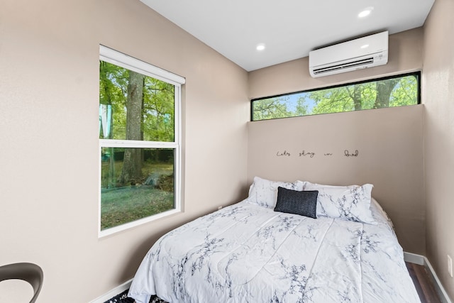 bedroom with an AC wall unit, multiple windows, and hardwood / wood-style flooring