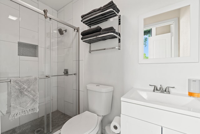 bathroom with toilet, vanity, and a shower with door