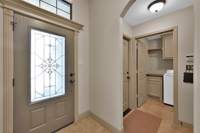 tiled foyer entrance featuring washer / clothes dryer and a healthy amount of sunlight