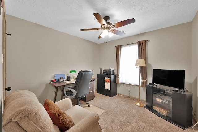 office area with light carpet, ceiling fan, and a textured ceiling