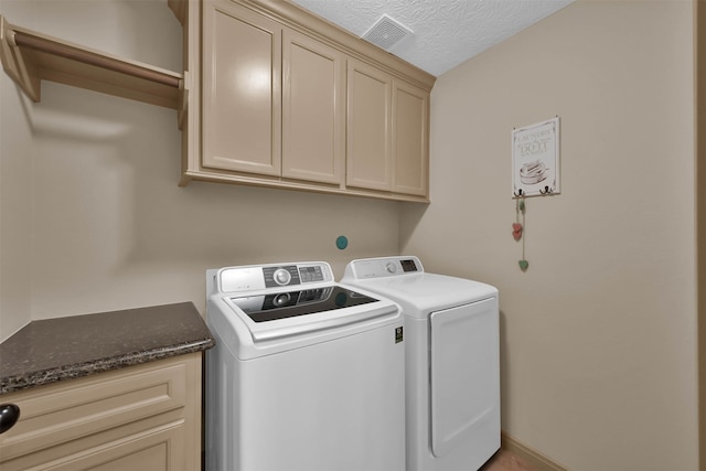 washroom with cabinets, separate washer and dryer, and a textured ceiling