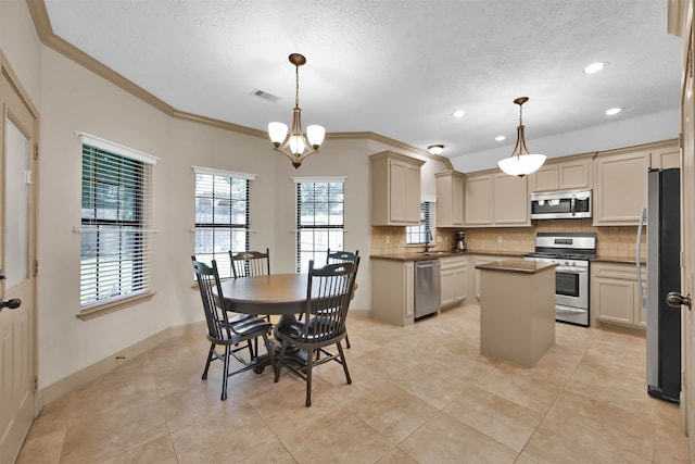 kitchen featuring a center island, hanging light fixtures, stainless steel appliances, cream cabinetry, and ornamental molding