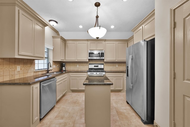 kitchen with stainless steel appliances, sink, cream cabinets, a kitchen island, and hanging light fixtures