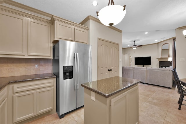 kitchen with ornamental molding, ceiling fan, cream cabinets, stainless steel fridge with ice dispenser, and a kitchen island