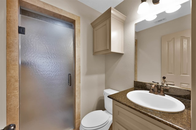 bathroom with a shower with door, vanity, and toilet