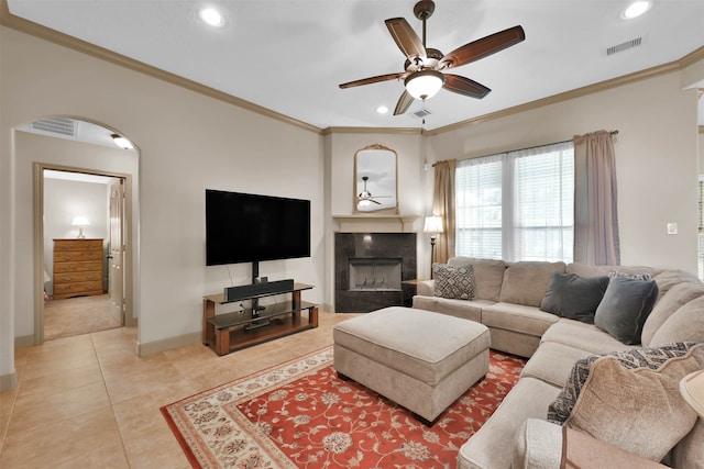 tiled living room with ceiling fan and crown molding