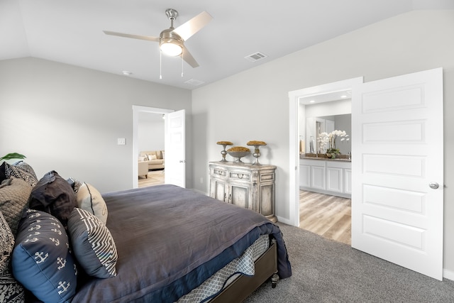 carpeted bedroom featuring connected bathroom, lofted ceiling, and ceiling fan