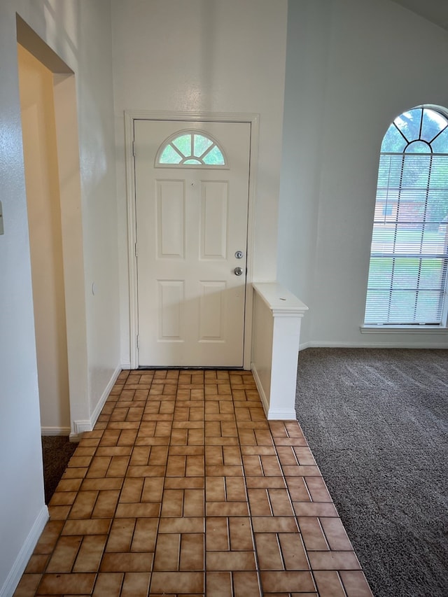 foyer with carpet and high vaulted ceiling