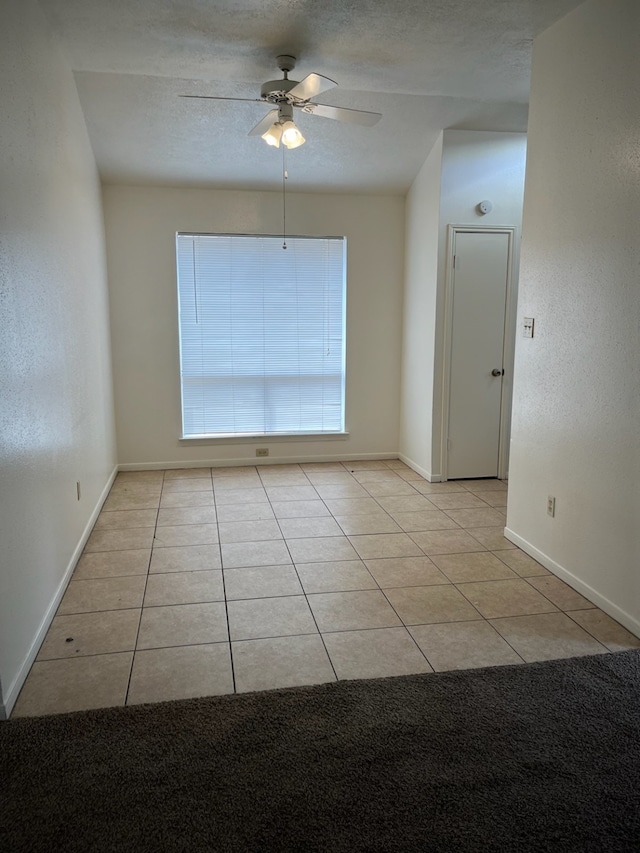 empty room with a textured ceiling, light tile patterned floors, and ceiling fan