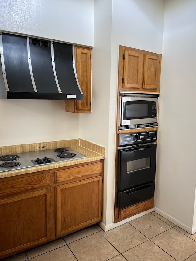 kitchen with appliances with stainless steel finishes, light tile patterned flooring, and exhaust hood