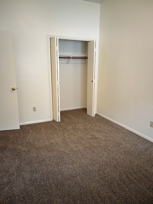 unfurnished bedroom featuring a closet and dark carpet